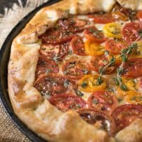 A close of a herbed tomato galette showing the colorful tomatoes and browned crust