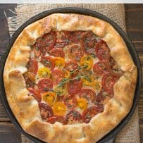 A galette viewed from overhead with yellow and red tomato slices in the center