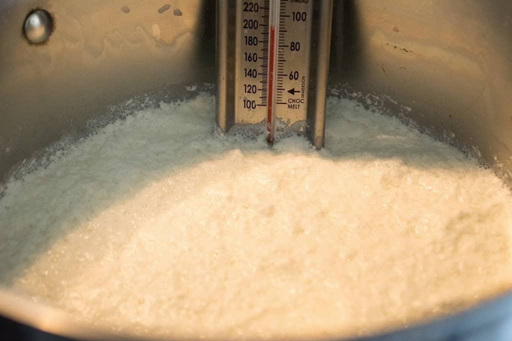 Whole milk cooking in a pan with a thermometer