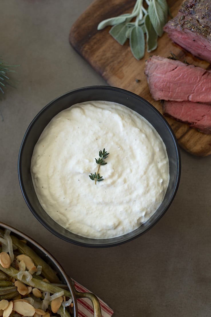 An overhead image of the horseradish garnished with fresh thyme with slices of beef and green beans