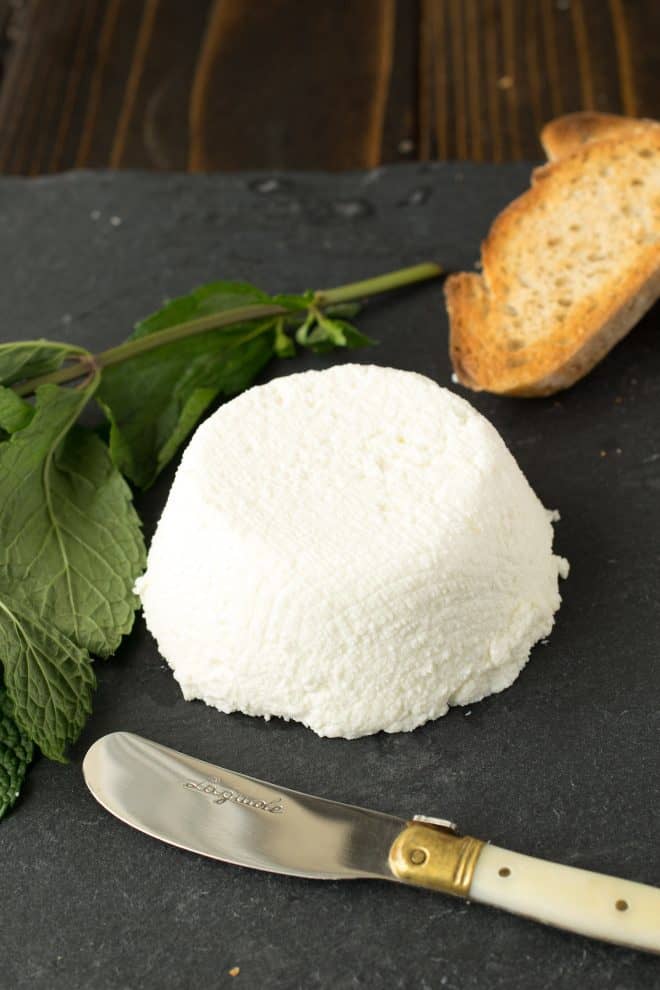 A mound of ricotta with crusty bread and a knife