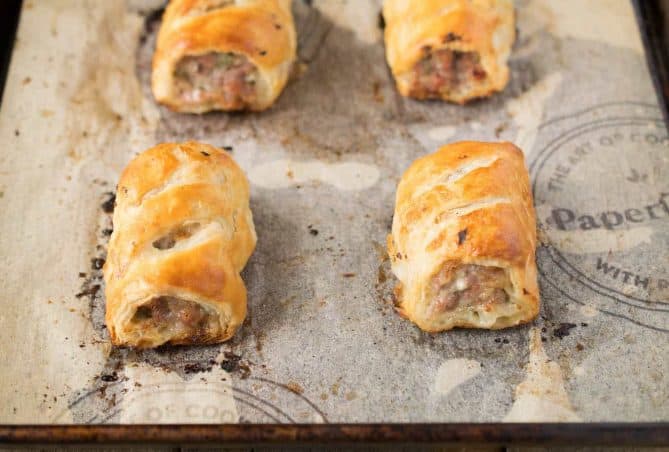 4 sausage rolls on a baking sheet fresh out of the oven