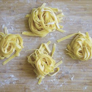 Freshly cut homemade tagliatelle pasta on a board