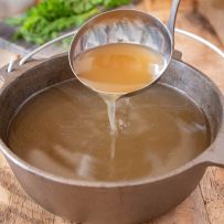 Pouring broth from a ladle into a pan