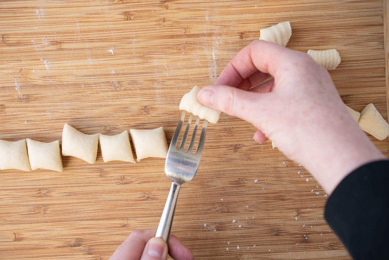 Rolling gnocchi dough balls over a fork to create the ridges