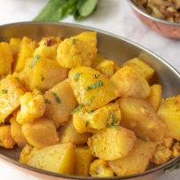 An oval serving dish full of Indian aloo gobi