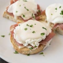 3 pieces of ciabatta bread topped with prosciutto, a poached egg and Parmesan sauce