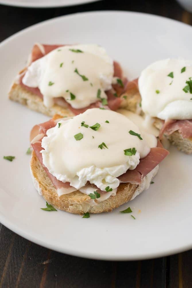 3 English muffins topped with prosciutto, a poached egg and Parmesan sauce