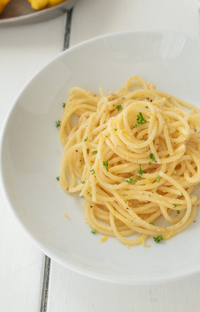 A closeup of lemon pepper spaghetti showing flecks of lemon and parsley