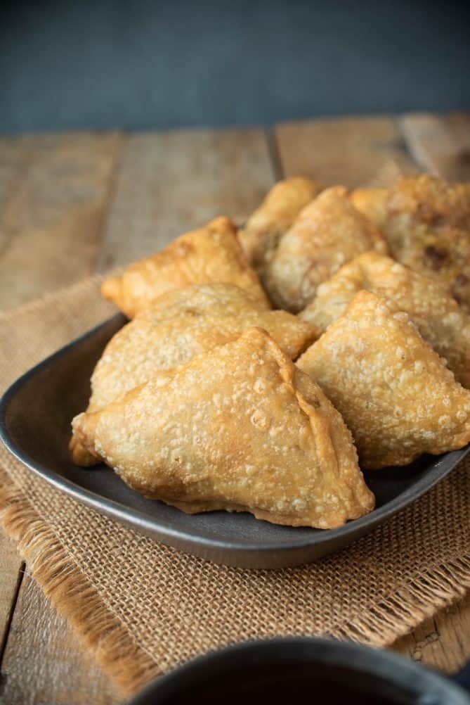 8 triangle shaped samosa on a pewter plate