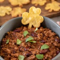 A hearty bowl of chili with a tortilla chip shaped like an Irish shamrock