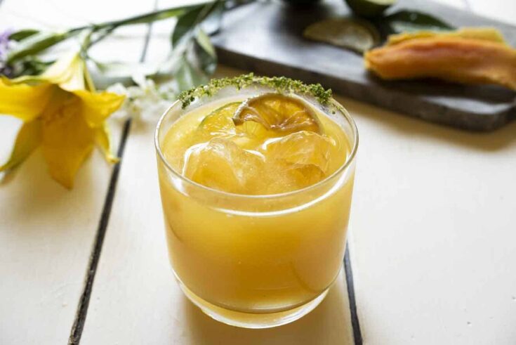 A glass of mango juice with ice and lime slices