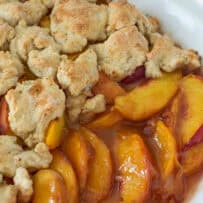A closeup of peach slices in a maple sauce with pastry pieces on top