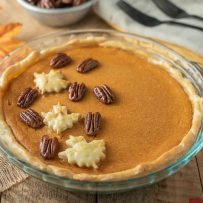 Maple Sweet Potato Pie in a glass pie pan garnished with pastry maple leaves and maple glazed pecans