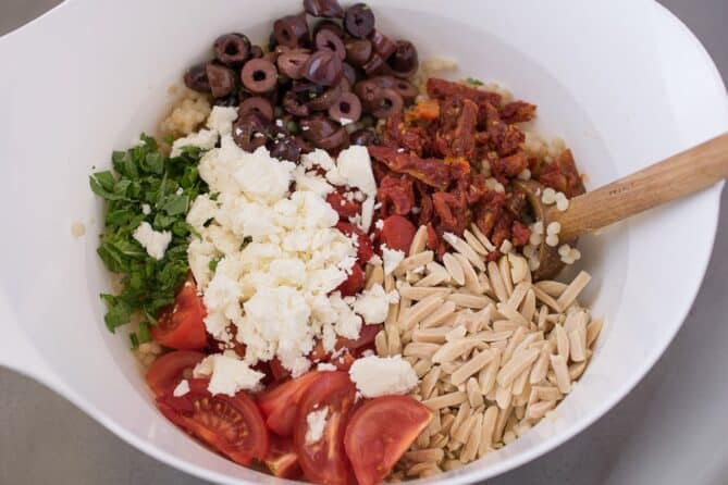 A bowl of olives, sun-dried tomatoes, almonds, feta cheese, mint and tomatoes