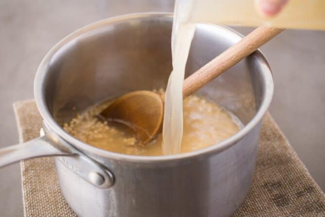 Pouring vegetable stock into a pan of couscous