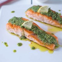 Mediterranean pesto salmon served on a white platter garnished with lemon