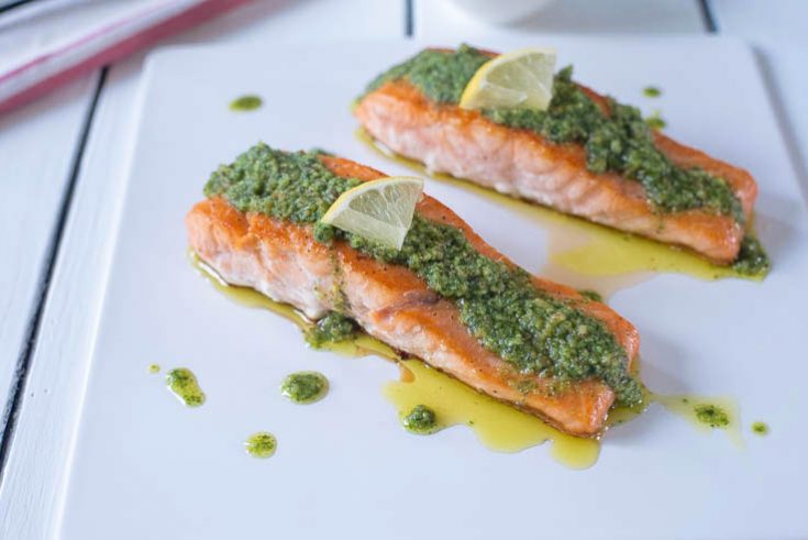 Mediterranean pesto salmon served on a white platter garnished with lemon