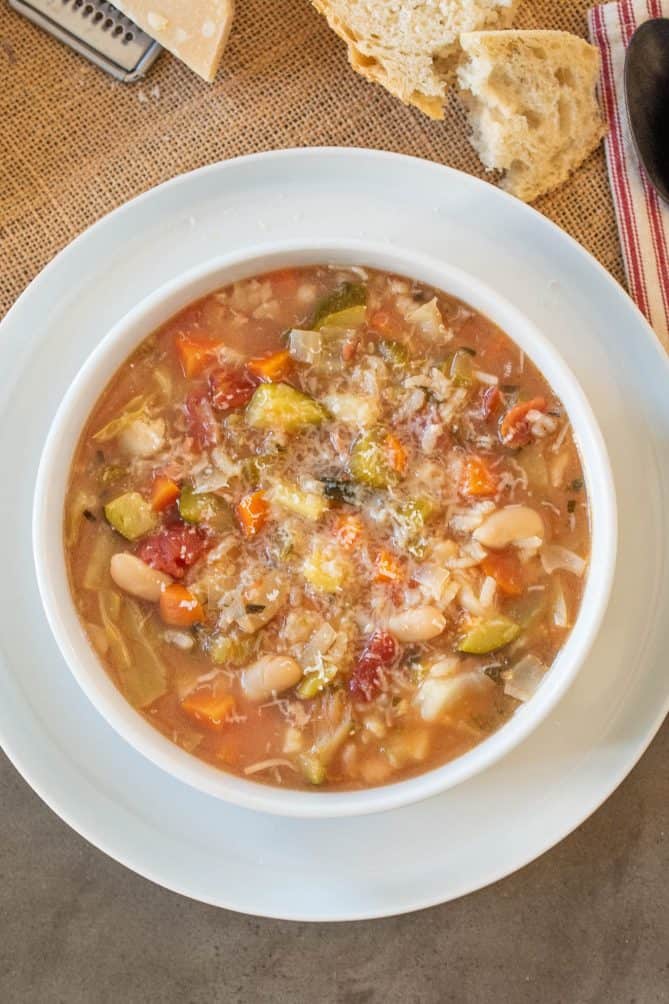 Viewed from overhead, a bowl of Milanese minestrone soup with bread