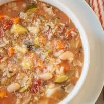A closeup of minestrone soup with beach, vegetables and grated Parmesan