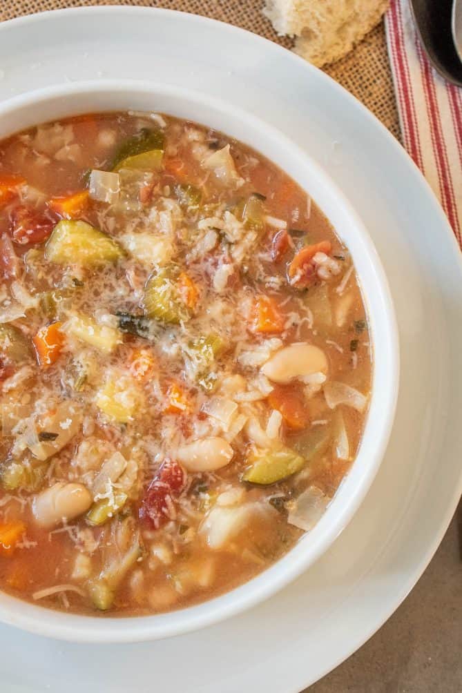 A closeup of minestrone soup with beach, vegetables and grated Parmesan