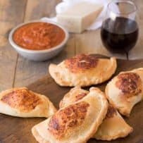 Mini ham and cheese calzones on a board with marinara sauce