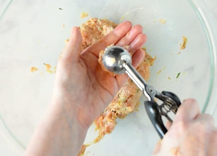 Using a mini scoop to shape mini meatballs.