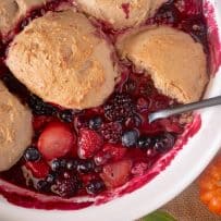 Spooning fruit cobbler out of a white bowl