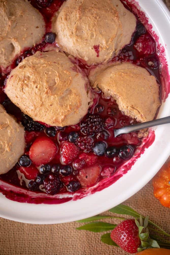 Spooning fruit cobbler out of a white bowl