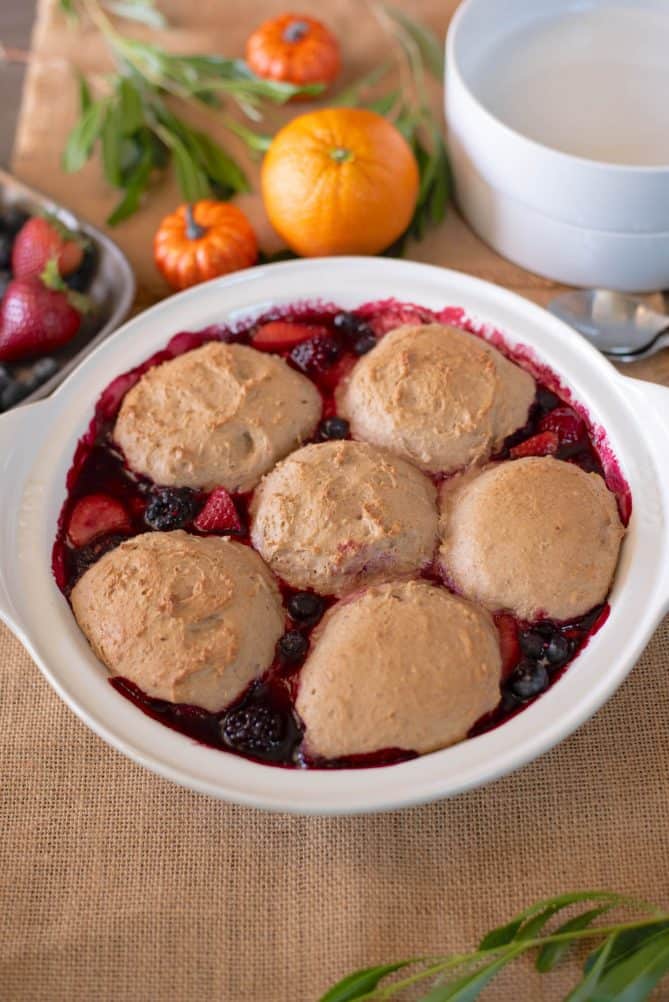 6 pecan dumplings on top of mixed berry cobbler in a white baking pan