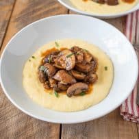 Mushroom sauce ragu served over polenta on a white plate