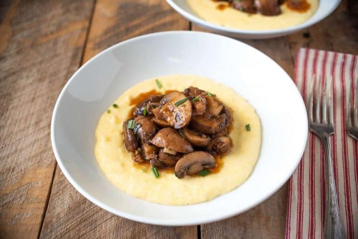 Creamy polenta is served topped with meaty mushroom pancetta ragu