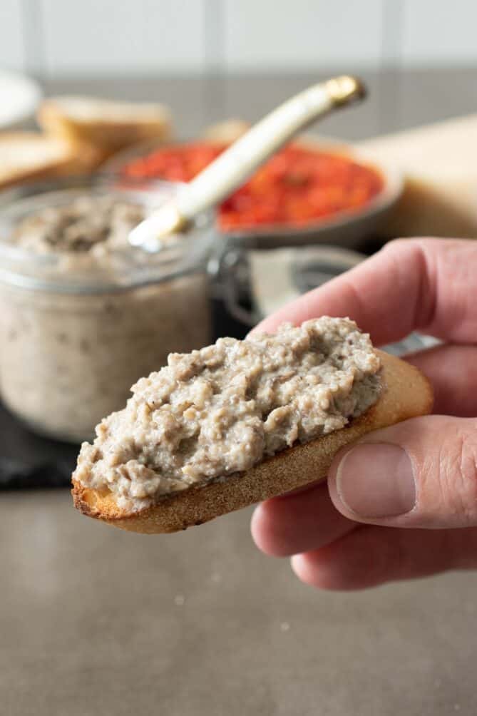 Holding a crostini topped with mushroom p&acirc;t&eacute;