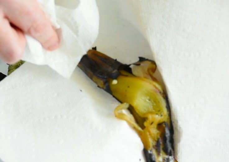 Paper towels being used to wipe the charred skin off green chiles