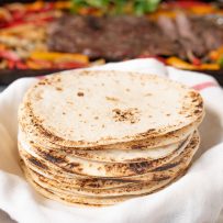 A stack of flour tortillas in a towel to keep them warm
