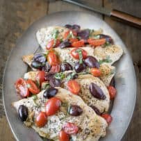 One pan chicken with tomatoes and olives on a silver serving platter