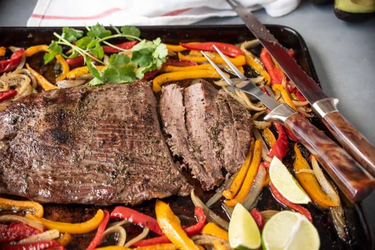 Sliced beef on a sheet pan with onions and peppers