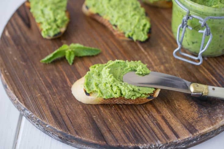 Spreading pea and mint pesto onto a crostini