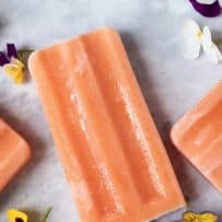 A peach colored popsicle (ice lolly) with purple, yellow and white flowers