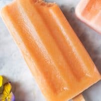 A bite taken out of a peach popsicle lying down on marble