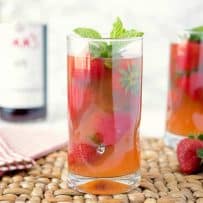 A side view of 2 glasses Pimm's strawberry mint cocktail showing all the strawberries in the glass