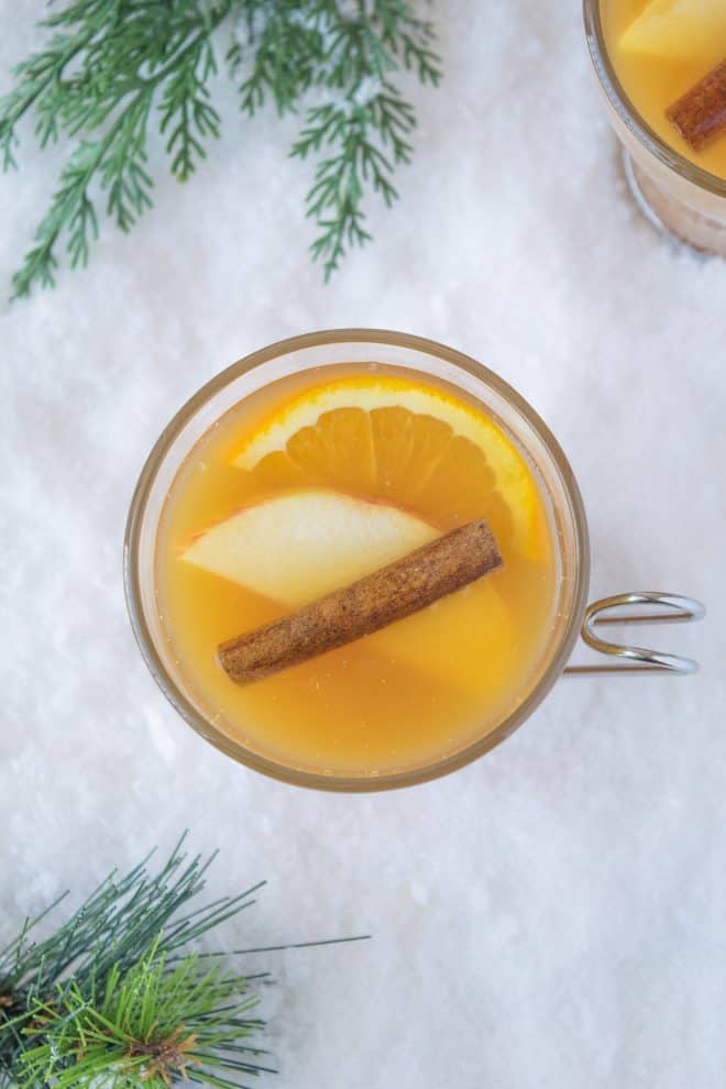 Showing from above the garnishes of cinnamon stick, apple slice and orange slice