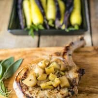 A pork chop on a cutting board topped with chopped apples