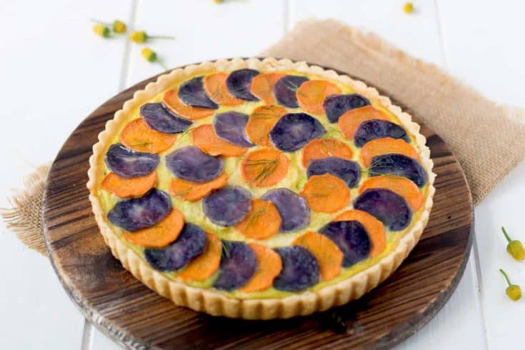 Potato and vegetable quiche topped with slices of orange and purple potatoes