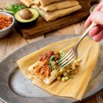 A tamale opened up with salsa and corn