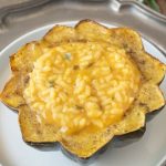 The inside of an acorn squash filled with pumpkin risotto on a white plate