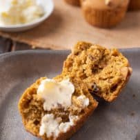 A pumpkin walnut muffin cut in half spread with butter