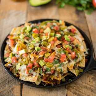 A round pan holding a pile of queso fundido nachos