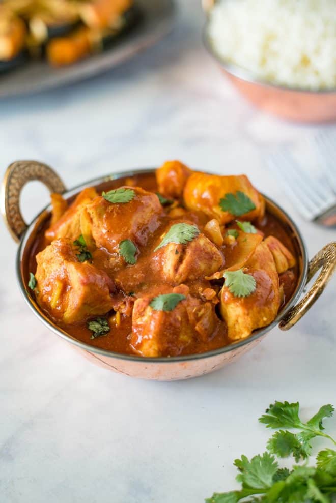 Chicken madras served in an Indian Karahi topped with fresh cilantro