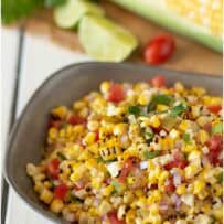 Yellow corn, red tomato and green salsa of a colorful corn salsa in a grey bowl